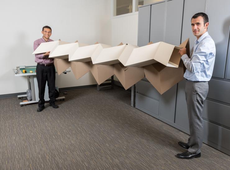 <p>Researchers Glaucio Paulino (left) and Evgueni Filipov show a large origami structure that can be folded into a much smaller space. Filipov is from University of Illinois at Urbana-Champaign; Paulino is from the Georgia Institute of Technology. (Credit: Rob Felt, Georgia Tech)</p>