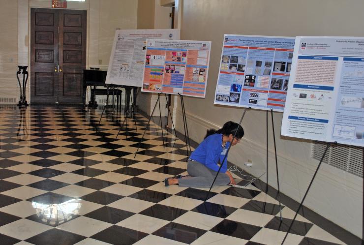<p>A presenter at the symposium makes last minute preparations among the posters in the halls of the Historic Academy of Medicine at Georgia Tech.</p>