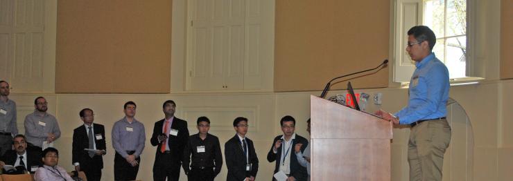<p>A long line of researchers waits their turn at the podium during rapid fire presentations.</p>
