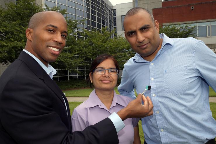 <p>Professor Baratunde Cola (left) holds a carbon nanotube optical rectenna device. With him are Asha Sharma (center) and Virendra Singh from his group, who are collaborators on the development. (Credit: Candler Hobbs, Georgia Tech)</p>