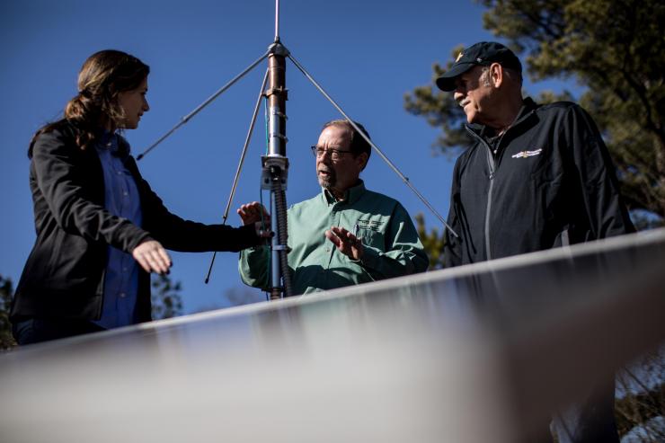<p>John Trostel, director of the Severe Storms Research Center (SSRC), Madeline Frank, a research meteorologist at the SSRC, and Tom Perry, an SSRC electrical engineer, examine equipment for the North Georgia Lightning Mapping Array, a network of 12 sensors located around the metropolitan Atlanta area to detect lightning that may indicate storm intensification. (Credit: Branden Camp, Georgia Tech Research Institute)</p>