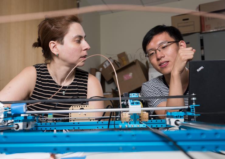 <p>Georgia Tech Assistant Professor Alenka Zajic and graduate student Derrick Chu discuss a device used to systematically measure side-channel outputs from electronic devices. (Credit: Rob Felt, Georgia Tech)</p>