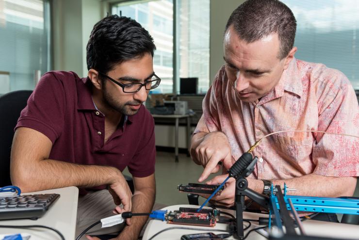 <p>Georgia Tech Professor Milos Prvulovic and graduate student Nader Sehatbakhsh discuss signal outputs from an electronic device. (Credit: Rob Felt, Georgia Tech)</p>