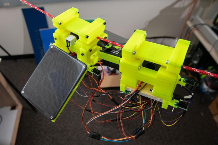 <p>Image shows components of the SlothBot, which is powered by two photovoltaic panels. 3D-printed gears and switches help the robot switch from one cable to another. (Photo: Allison Carter)</p>