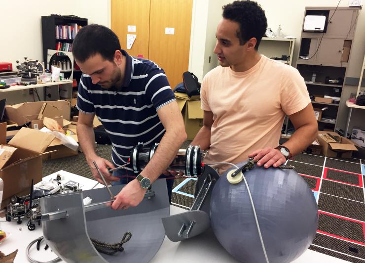 <p>Georgia Tech graduate research assistants Yousef Emam and Gennaro Notomista assemble SlothBot in the laboratory of Magnus Egerstedt. SlothBot is a slow-moving and energy-efficient robot that can linger in the trees to monitor animals, plants, and the environment below. (Credit: John Toon, Georgia Tech)</p>