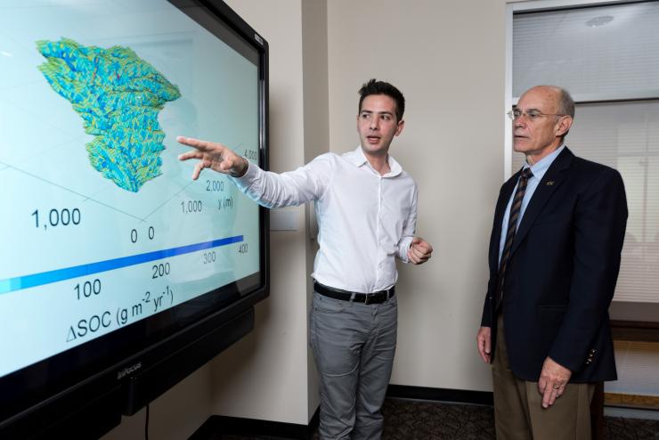 <p>Yannis Dialynas, a hydrology Ph.D. student in Georgia Tech’s School of Civil and Environmental Engineering, and Georgia Tech Provost Rafael L. Bras, discuss a model of soil erosion. This research is studying the role of erosion on carbon cycling. (Credit: Rob Felt, Georgia Tech)</p>