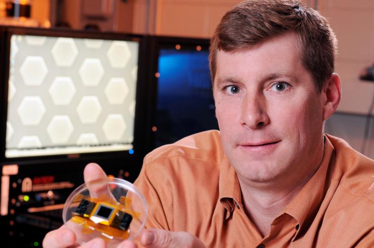 <p>Jud Ready, GTRI principal investigator, shows a solar cell produced from earth-abundant materials. In the background is the plasma enhanced CVD tool used to grow the carbon nanotube arrays. (Credit: Gary Meek, Georgia Tech)</p>