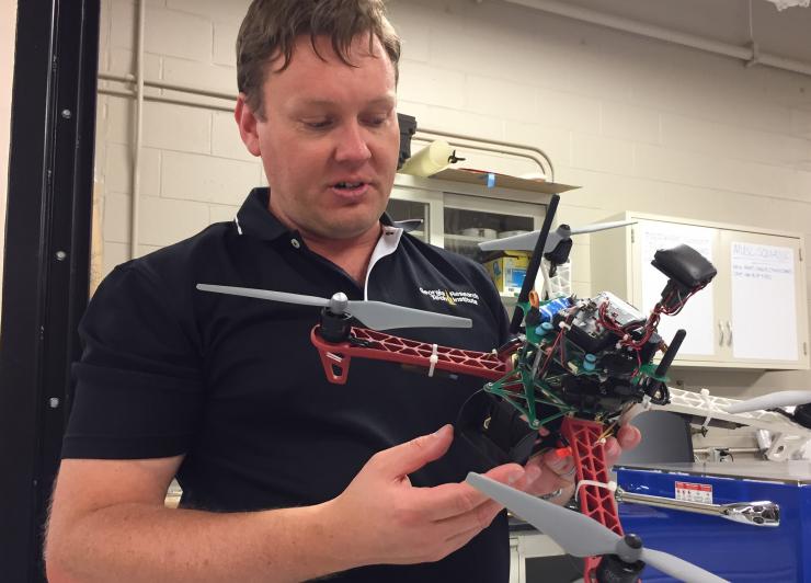 <p>Warren Lee, branch head for GTRI’s Unmanned Flight Operations, holds a quadcopter of the type used in the competition. The aircraft were assembled, modified and tested at GTRI. (Credit: John Toon, Georgia Tech)</p>