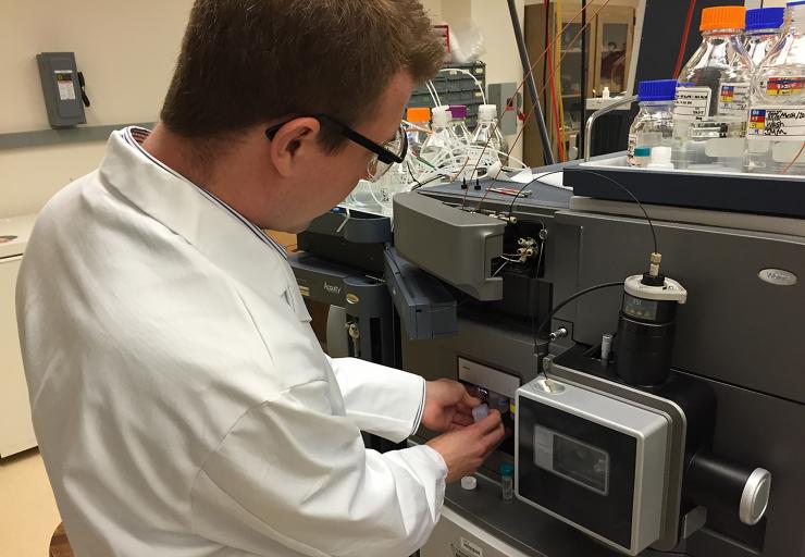<p>Georgia Tech postdoctoral fellow Jay Forsythe loads a sample into a mass spectrometer. The testing was done to see what compounds were formed by subjecting mixtures of amino and hydroxy acids to repeated wet-dry cycles. (Photo: John Toon, Georgia Tech)</p>