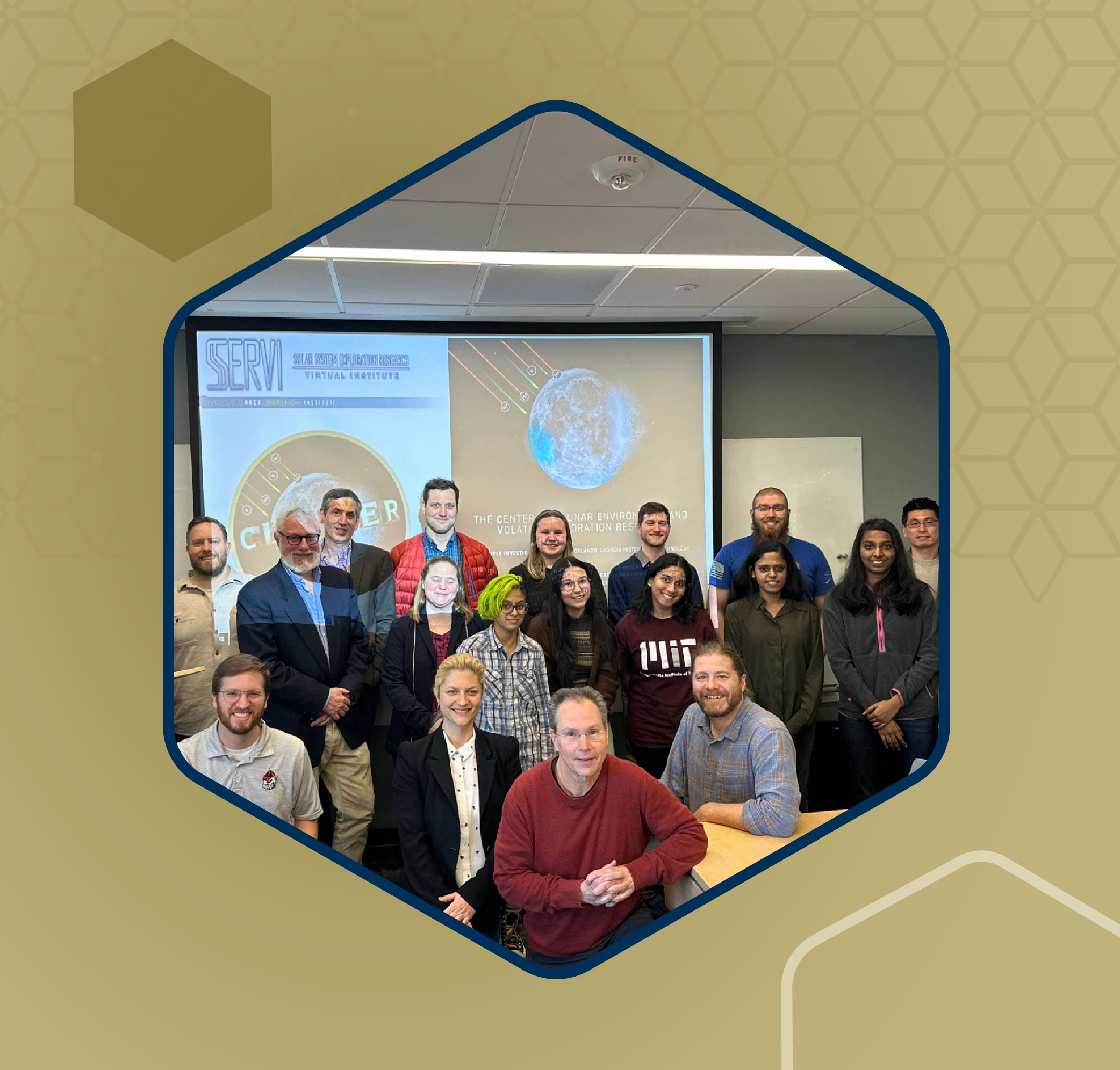 Group photo of researchers and students standing and seated in a classroom with a presentation slide displayed on a screen behind them.