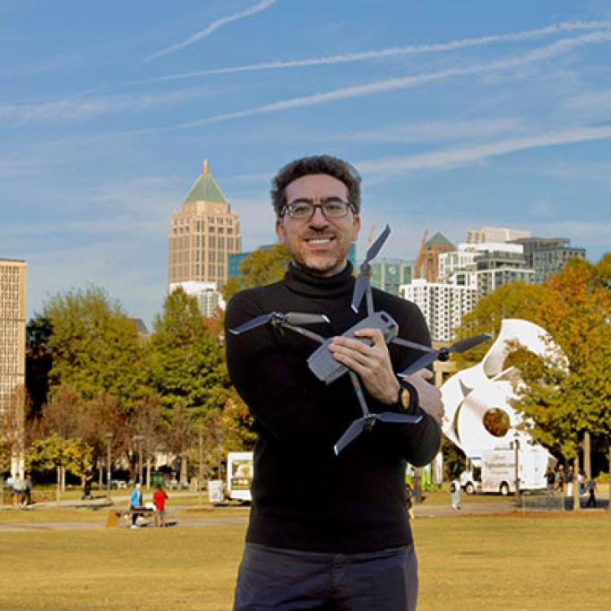 Tarek Rakha on the Georgia Tech campus holding a drone in his arms.