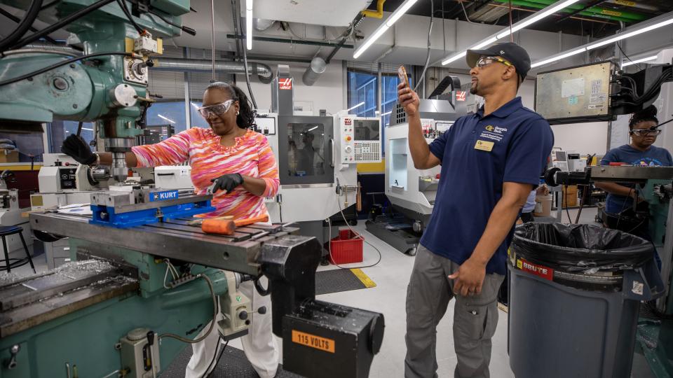 A participant at a Georgia Tech manufacturing workshop cuts metal on industrial equipment. 