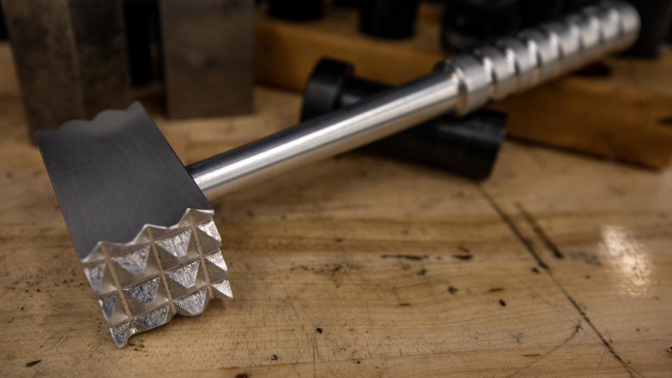 A metal meat tenderizer with a textured striking surface created by participants at a Georgia Tech workshop. 