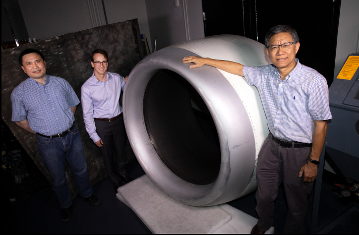 The Georgia Tech Center for Composite and Hybrid Materials Interfacing site leadership team stands by an aircraft engine