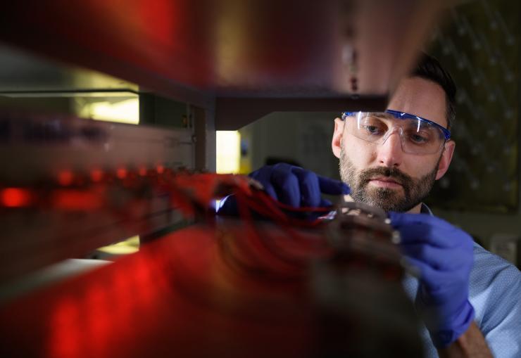 <p>Matthew McDowell, an assistant professor in the George W. Woodruff School of Mechanical Engineering and the School of Materials Science and Engineering, examines batteries in a cycling station. (Credit: Rob Felt)</p>