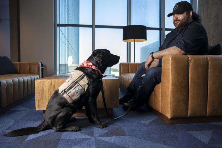 <p><em>GTRI Research Associate Alex Montañez sits with his service dog Willow. (Photo Credit: Sean McNeil)</em></p>