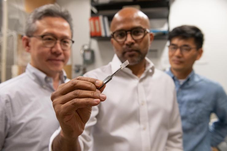 <p>Seung Soon Jang, an associate professor, Faisal Alamgir, an associate professor, and Ji Il Choi, a postdoctoral researcher, all in Georgia Tech’s School of Materials Science and Engineering, examine a piece of platinum-graphene catalyst. (Credit: Allison Carter)</p>