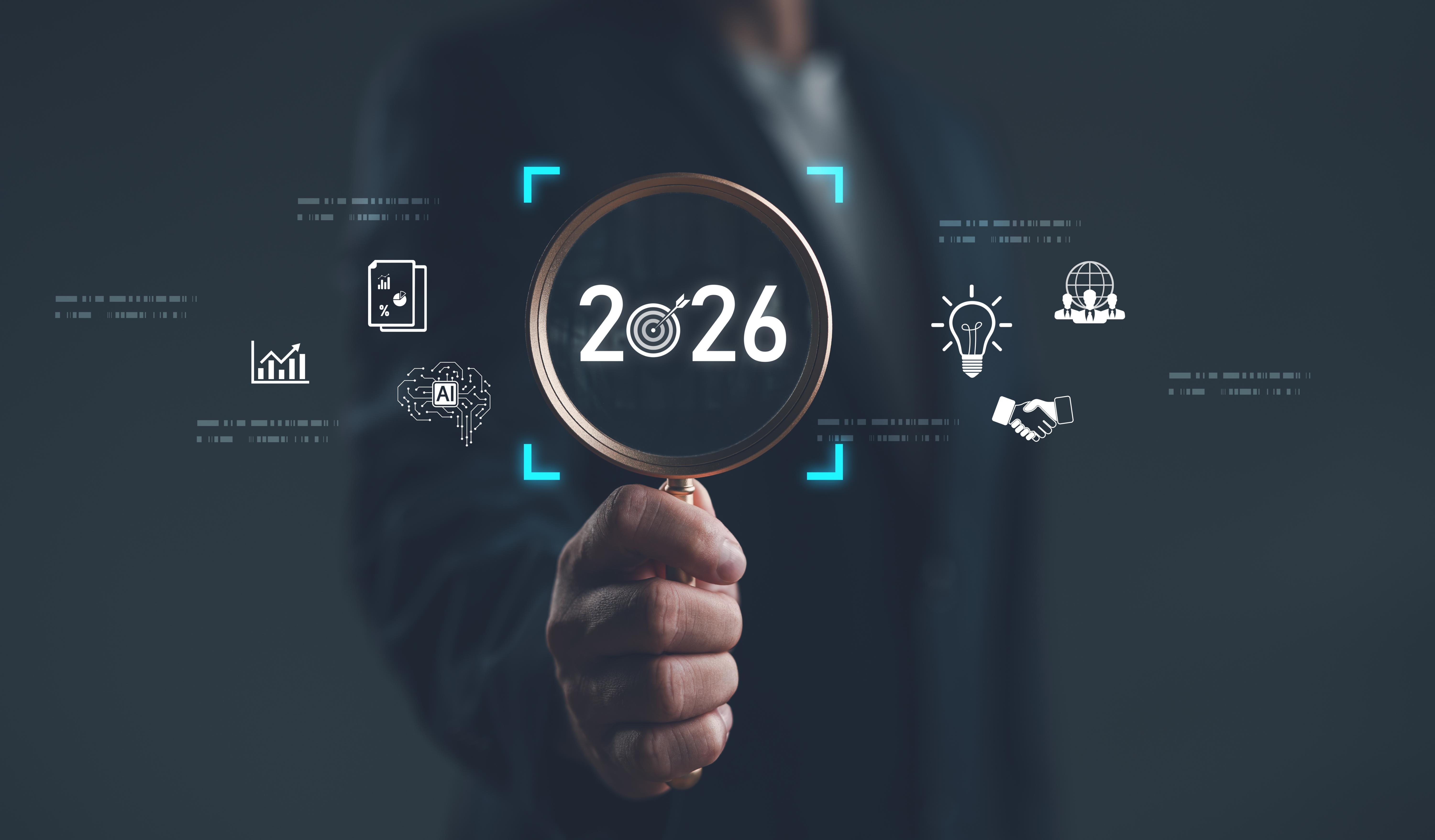 Businessman holding magnifying glass focusing on year 2026 with digital icons of innovation, AI, analytics, and global strategy. Concept of future planning, technology trends and vision. 