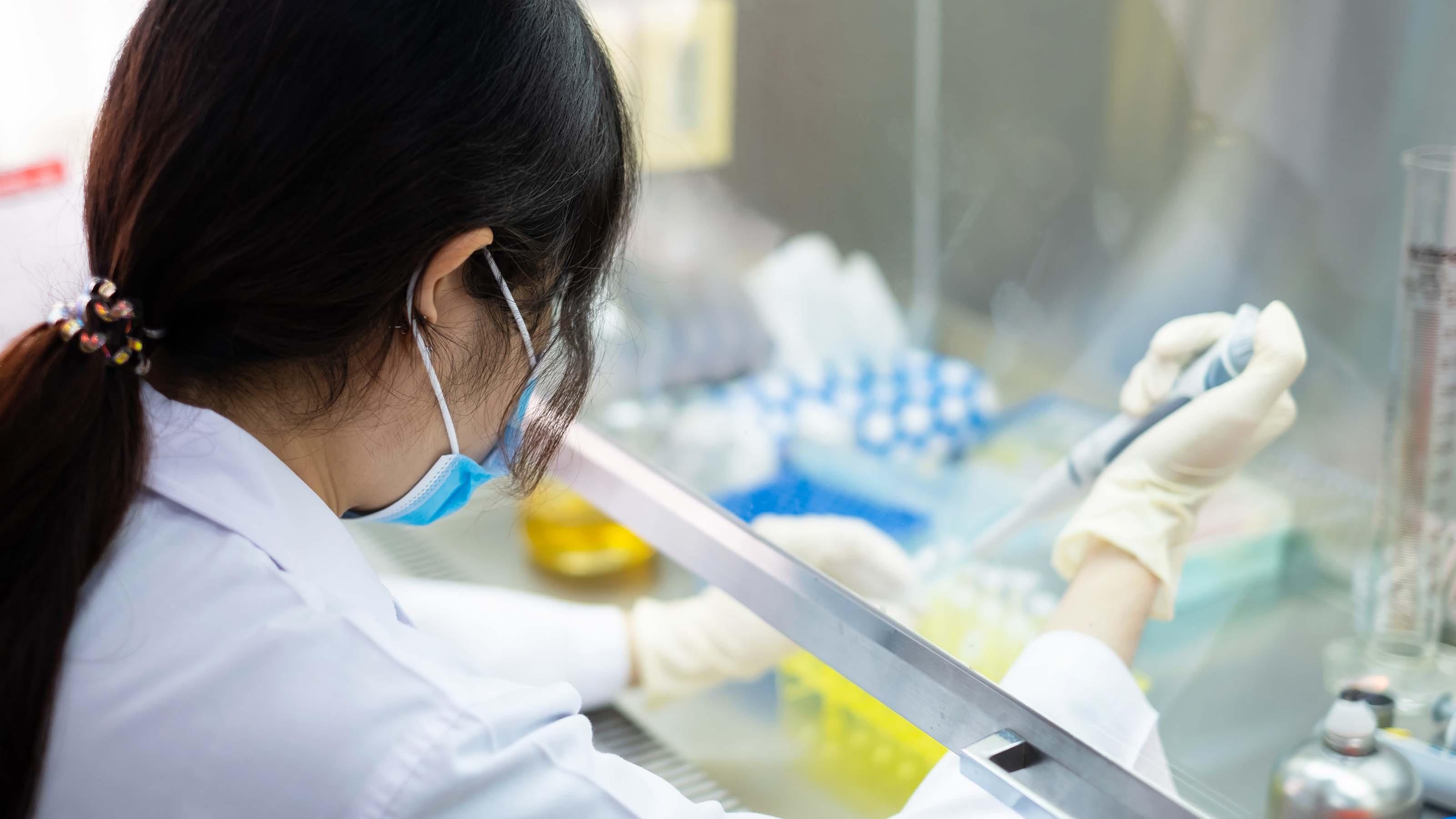 A lab worker fills pipettes.