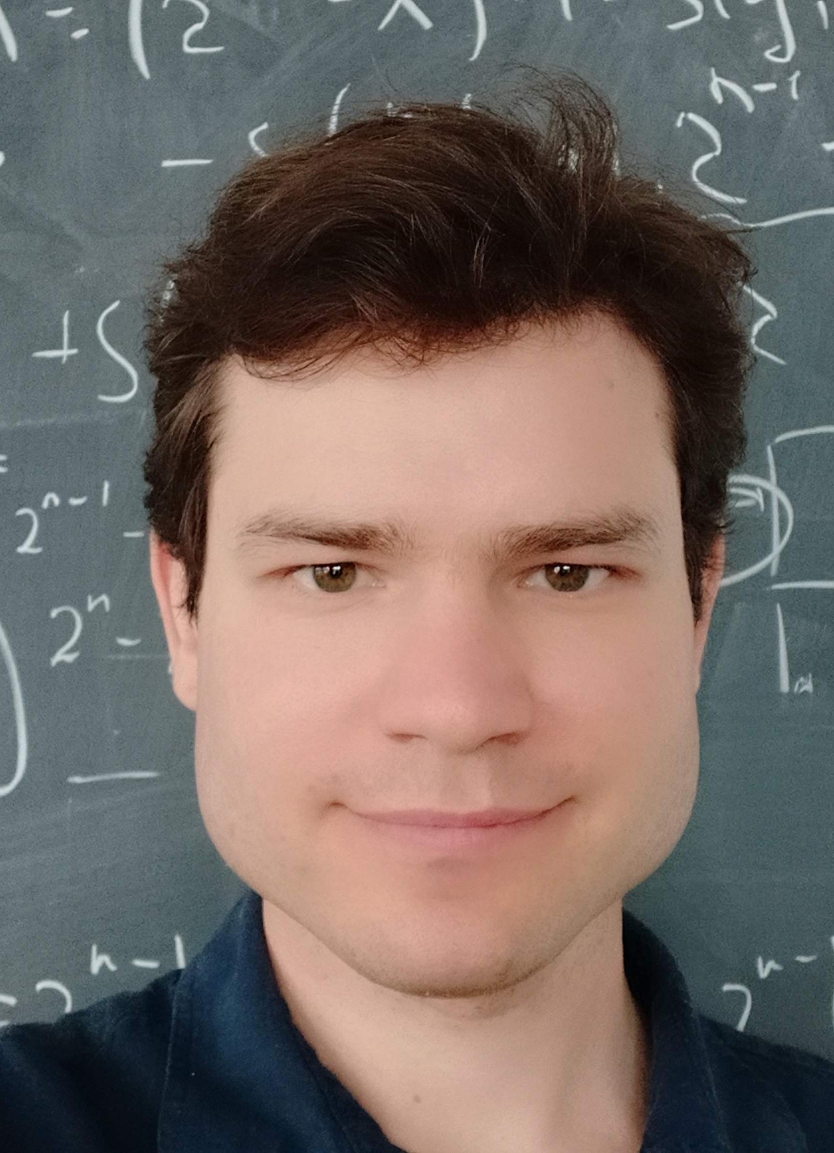 A portrait of Anton Bernshteyn. He is standing in front of a chalkboard that is covered with mathematical equations.