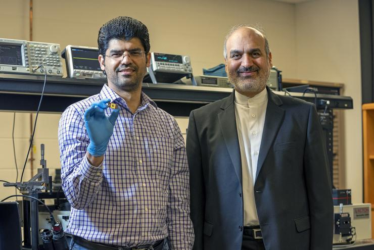 <p>ECE professor Ali Adibi with Ph.D. candidate Sajjad Abdollahramezani holding their packaged tunable metasurface device.</p>
