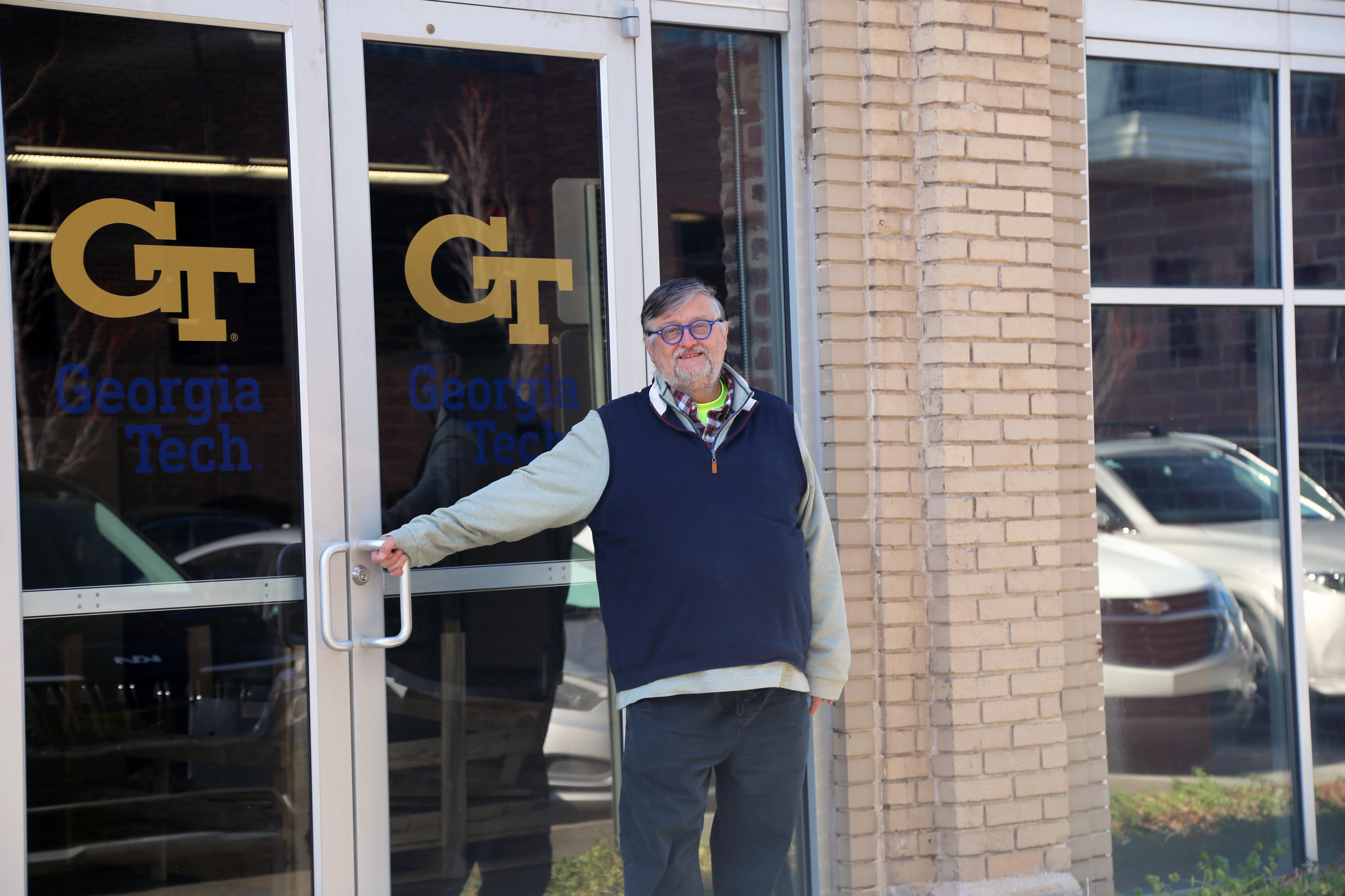 A man standing in front of glass double doors with the Georgia Tech logo.