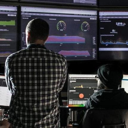 Two cybersecurity specialists monitor network activity.