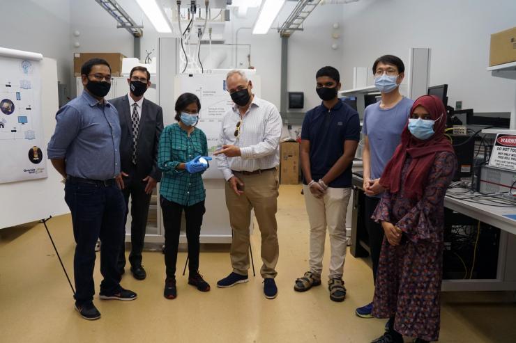 <p>Nujhat Tasneem (third from left) shows a FEFET chip fabricated at IEN to President Ángel Cabrera at a visit to the Khan Lab on August 18. Pictured left to right are Asif Khan, Douglas Blough, Tasneem, Cabrera, Prasanna Ravindran, Chinsung Park, and Nashrah Afroze.</p>