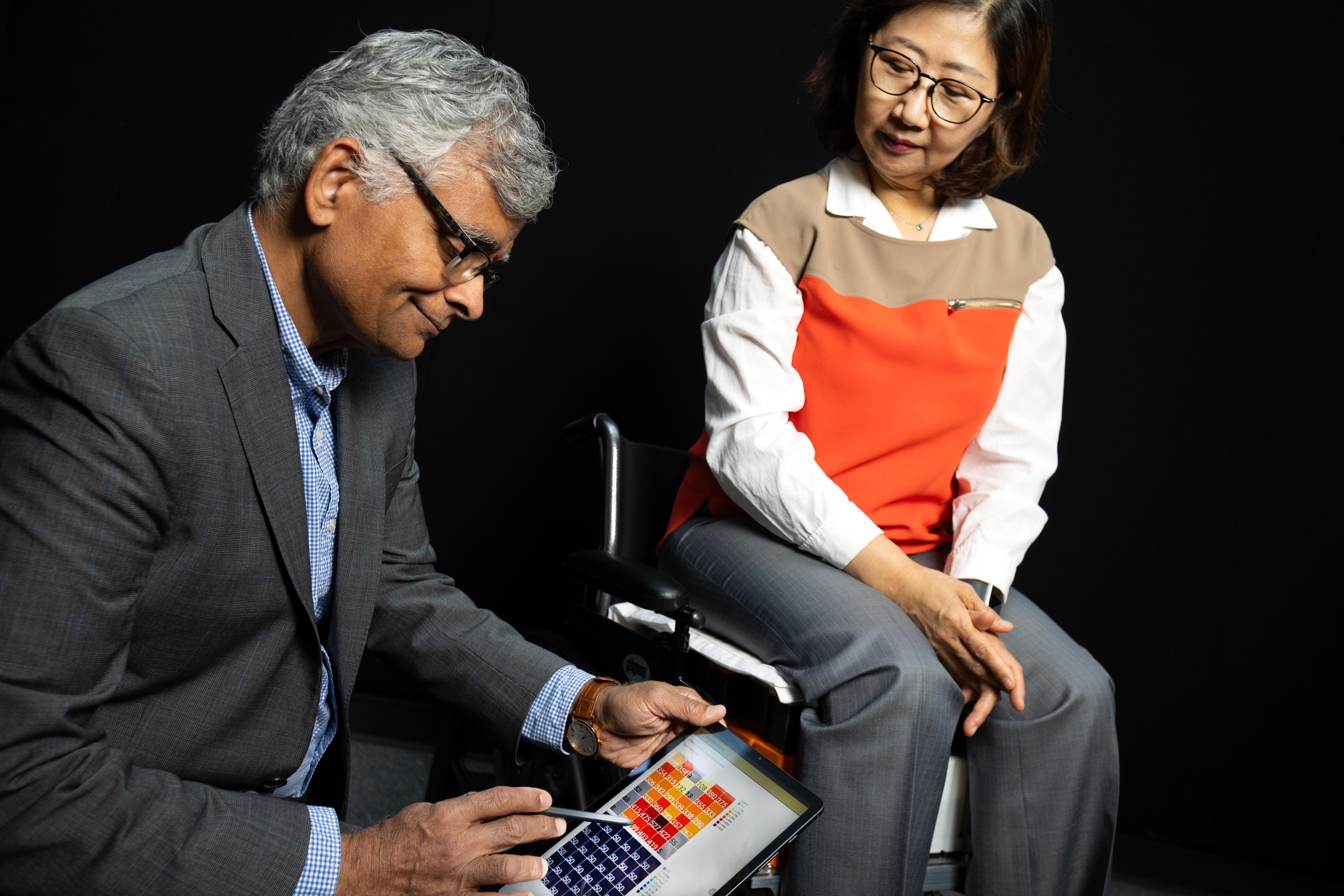   Sundaresan Jayaraman (left) looks at pressure data from fabric sensors he developed with Sungmee Park, who is seated in their prototype wheelchair system. (Photo: Candler Hobbs)