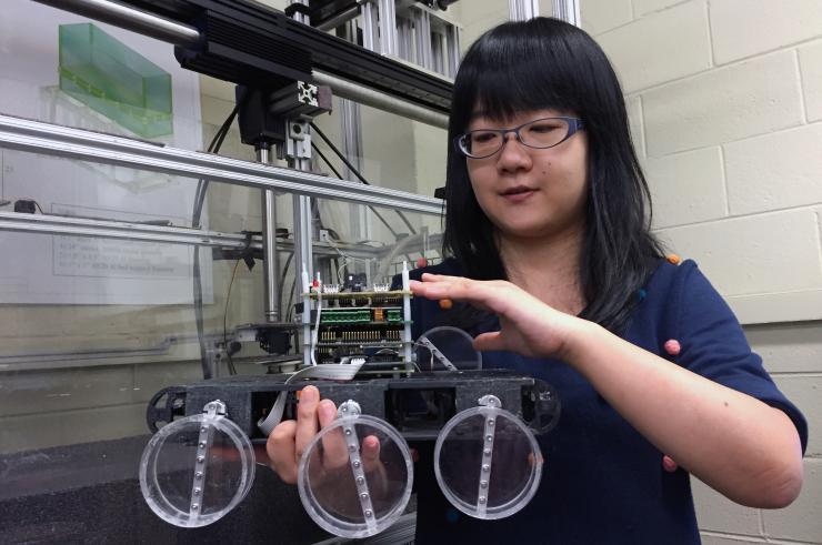 <p>Georgia Tech graduate student Feifei Qian shows details of the Sandbot, a bio-inspired hexapedal robot that was used to study how the stiffness of a loosely-packed surface affects the ability to move across it. The robot’s capabilities were compared to those of five desert-dwelling animals, including lizards and crabs. (Credit: John Toon, Georgia Tech)</p>