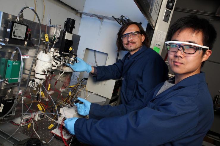 <p>Georgia Tech professor Andrei Fedorov (left) and undergraduate research assistant Yuzhe Peng are shown with the laboratory-scale hydrogen reforming system that produces the green fuel at relatively low temperature in a process that can be scaled up or down to meet specific needs. (Credit: Candler Hobbs, Georgia Tech)</p>