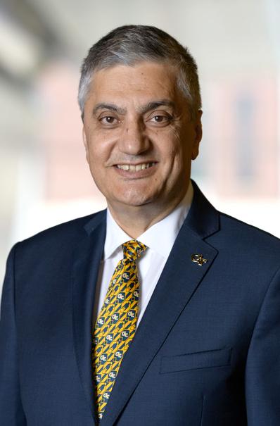 Headshot of Chaouki Abdallah wearing a navy suit jacket and gold-patterned tie with a white a shirt. Chaouki is smiling.