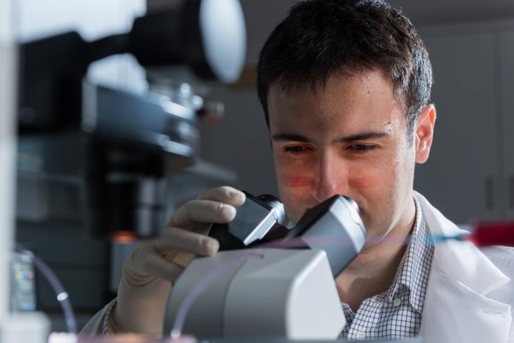 <p>Fatih Sarioglu, an assistant professor in the Georgia Tech School of Electrical and Computer Engineering, is shown examining a microfluidic device designed to capture cancer cell clusters. (Credit: Rob Felt)</p>