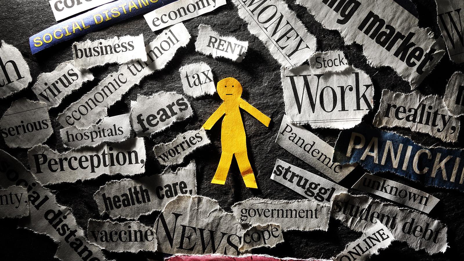 A yellow paper cutout of a person surrounded by Covid-19 related headlines