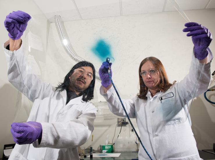 <p>Georgia Tech researchers Eric Shen and Anna Osterholm demonstrate how films of electrochromic polymers can be applied to large surfaces. (Credit: Rob Felt)</p>