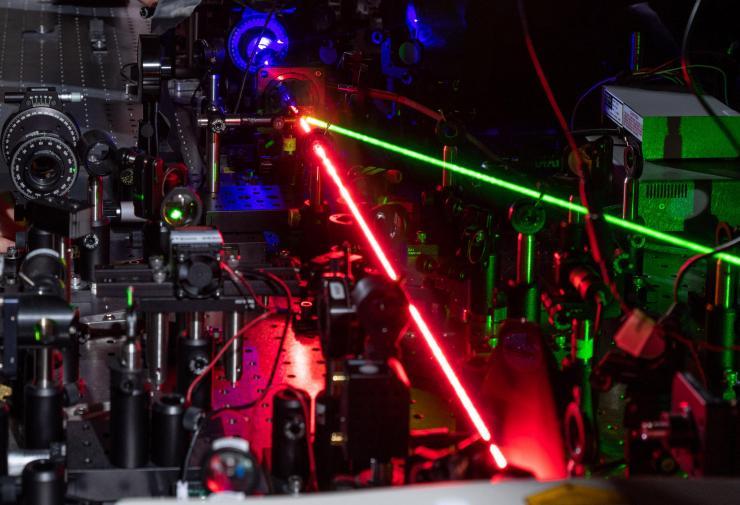 <p>A red laser creates nonlinear effects with tiny triangles of gold. The blue beam shows the frequency-doubled light and the green beam controls the hot-electron migration. (Credit: Rob Felt, Georgia Tech)</p>
