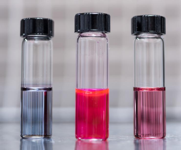 <p>Image shows vials containing samples of hairy nanoparticles. The right and left images contain photo-responsive polymer-capped gold nanoparticles prior to and after self-assembly, respectively. The center vial shows dye released from self-assembled gold nanoparticles. The nanoparticles are made with light-sensitive materials that assemble and disassemble themselves when exposed to light of different wavelengths. (Credit: Rob Felt, Georgia Tech)</p>