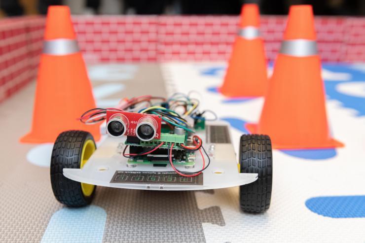 <p>A robotic car controlled by an ultra-low power hybrid chip is shown in an arena to demonstrate its ability to learn and collaborate with another robot. (Photo: Allison Carter, Georgia Tech)</p>