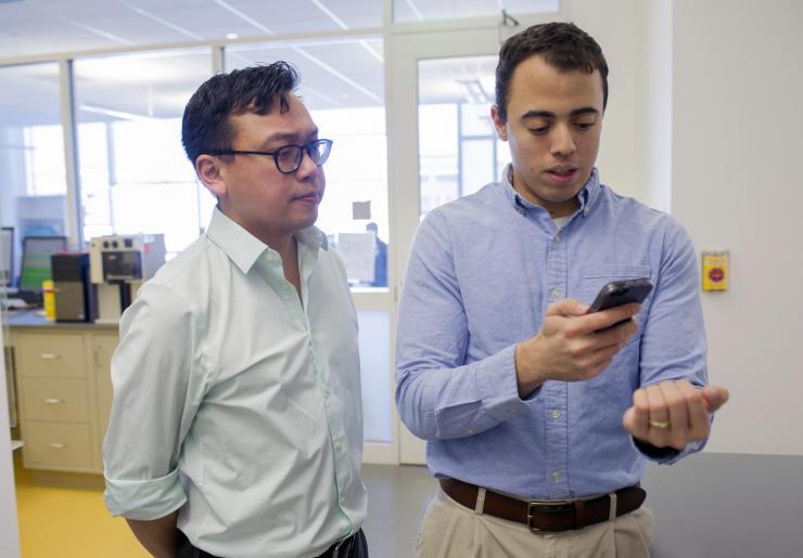 <p>Graduate student Rob Mannino (right), pictured with Wilbur Lam (left), looks at his own fingernails using the new anemia test app. Credit: Georgia Tech / Christopher Moore</p>