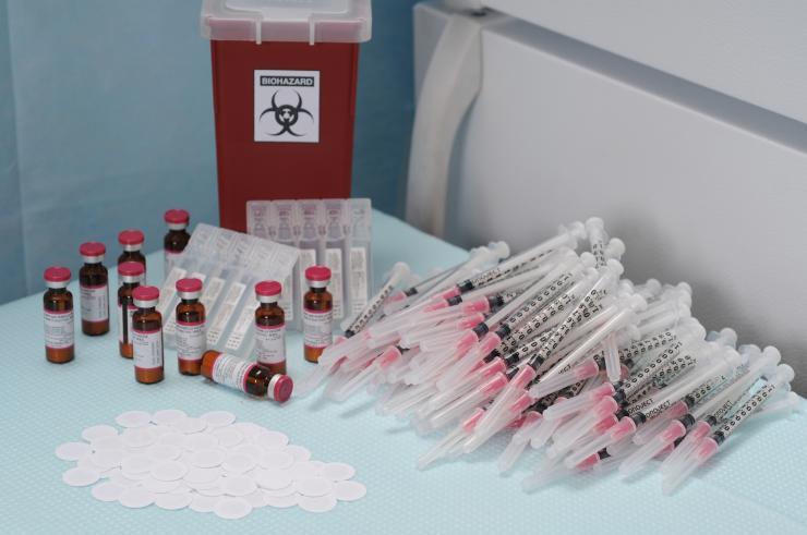 <p>The 100 microneedle patches (white) in the foreground could replace everything in the background: the 100 needles and syringes, 10 ten-dose vials of measles vaccine with diluent, a biohazards box for sharps waste disposal, and a refrigerator for cold chain storage. (Photo: Gary Meek)</p>