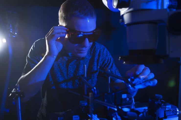 <p>NSF Graduate Research Fellow Erik Anderson tests the conversion of blue light to electricity with a new higher efficiency rectenna design. (Credit: Christopher Moore, Georgia Tech)</p>