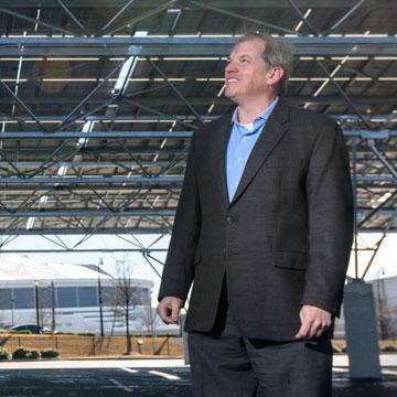 <p>Norman “Finn” Findley, CEO of the startup Quest Renewables, stands beneath his company’s QuadPod Solar Canopy system. Solar canopies are high ground-clearance structures designed for solar panels, but they also function as carports by providing shade for vehicles parked beneath them.</p>