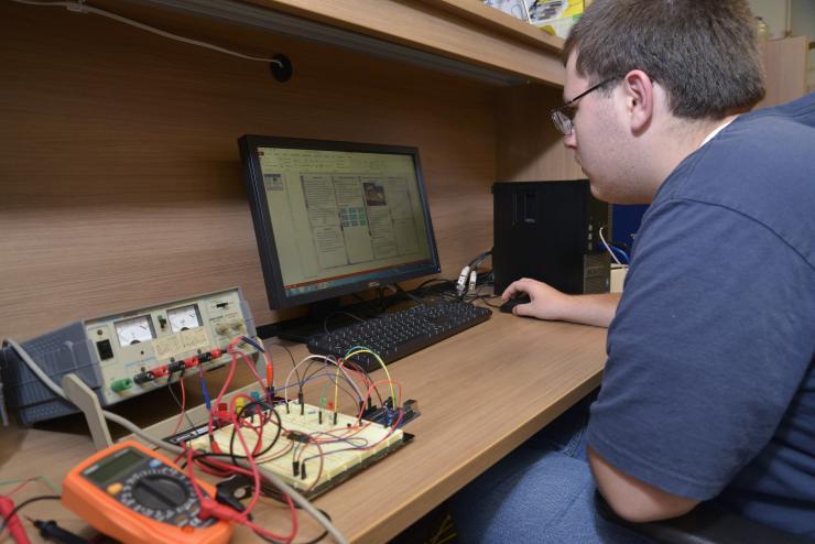 <p>Austin Pettit of Lithia Springs High School works out the details of the control system of a hybrid-electric unmanned aerial vehicle. (Credit: Rick Robinson)</p>