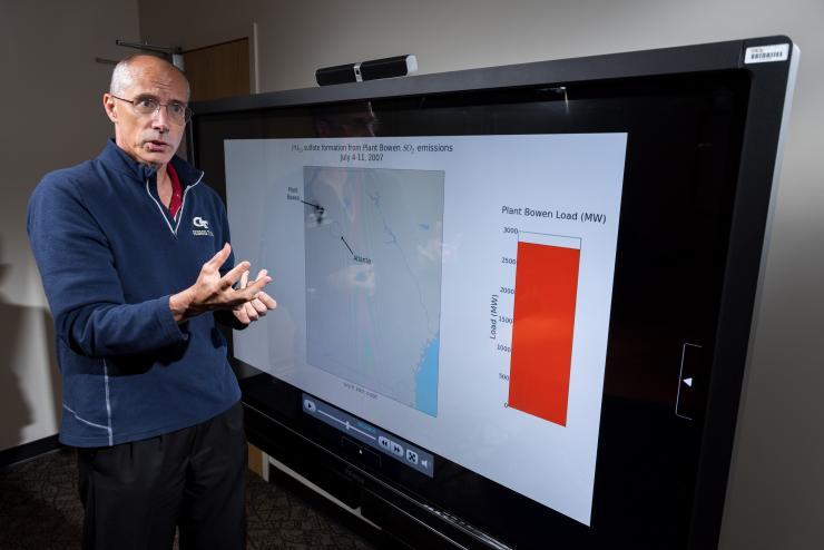 <p>Georgia Tech professor Armistead Russell with an air quality prediction model showing how the impacts from generating plant emissions vary over time. Having real-time information about the impacts could allow utility companies to operate plants to minimize effects on population centers. (Credit: Rob Felt, Georgia Tech)</p>