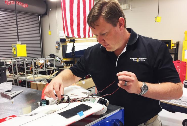 <p>Warren Lee, branch head for GTRI’s Unmanned Flight Operations, connects electronics in a Zephyr fixed-wing aircraft of the type used in the competition. (Credit: John Toon, Georgia Tech)</p>