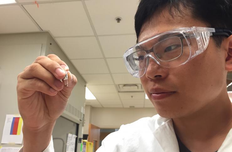 <p>Georgia Tech graduate student Sheng-Sheng Yu holds a sample that has been subjected to repeated cycles of wet-dry conditions. From amino acids and hydroxy acids, the process results in a mixture of polyesters and peptides containing as many as 14 units. (Photo: John Toon, Georgia Tech)</p>