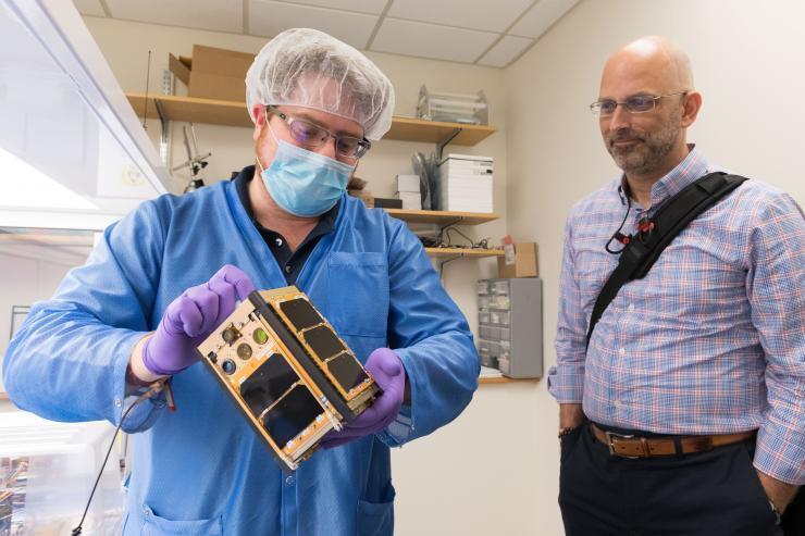 <p>Georgia Tech aerospace engineering graduate student Byron Davis shows Xenesis CEO Mark LaPenna one of the RANGE CubeSats scheduled to go into orbit later this fall. (Credit: Allison Carter, Georgia Tech)</p>