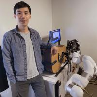 Georgia Tech researcher Ning Yang standing next to the robot guitarist.