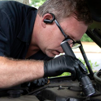 mechanic looking into car engine 