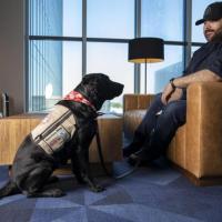 <p><em>GTRI Research Associate Alex Montañez sits with his service dog Willow. (Photo Credit: Sean McNeil)</em></p>